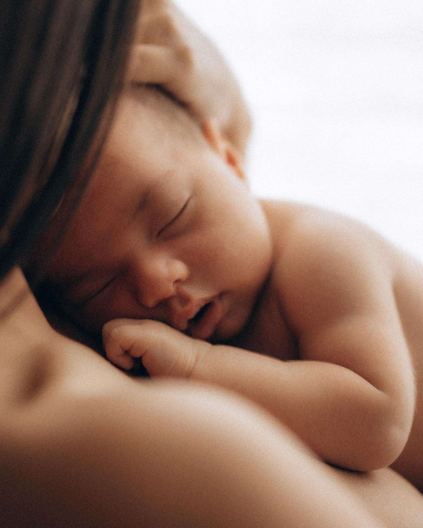A woman gently cradles a baby on her chest, showcasing a tender moment of bonding and affection between them.
